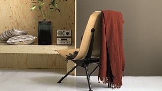 Een stoel met een rode deken en houten meubels.